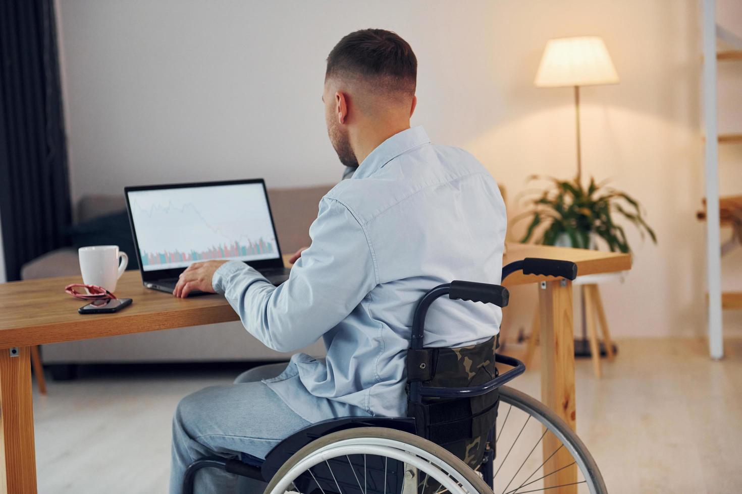 Business worker. Disabled man in wheelchair is at home photo