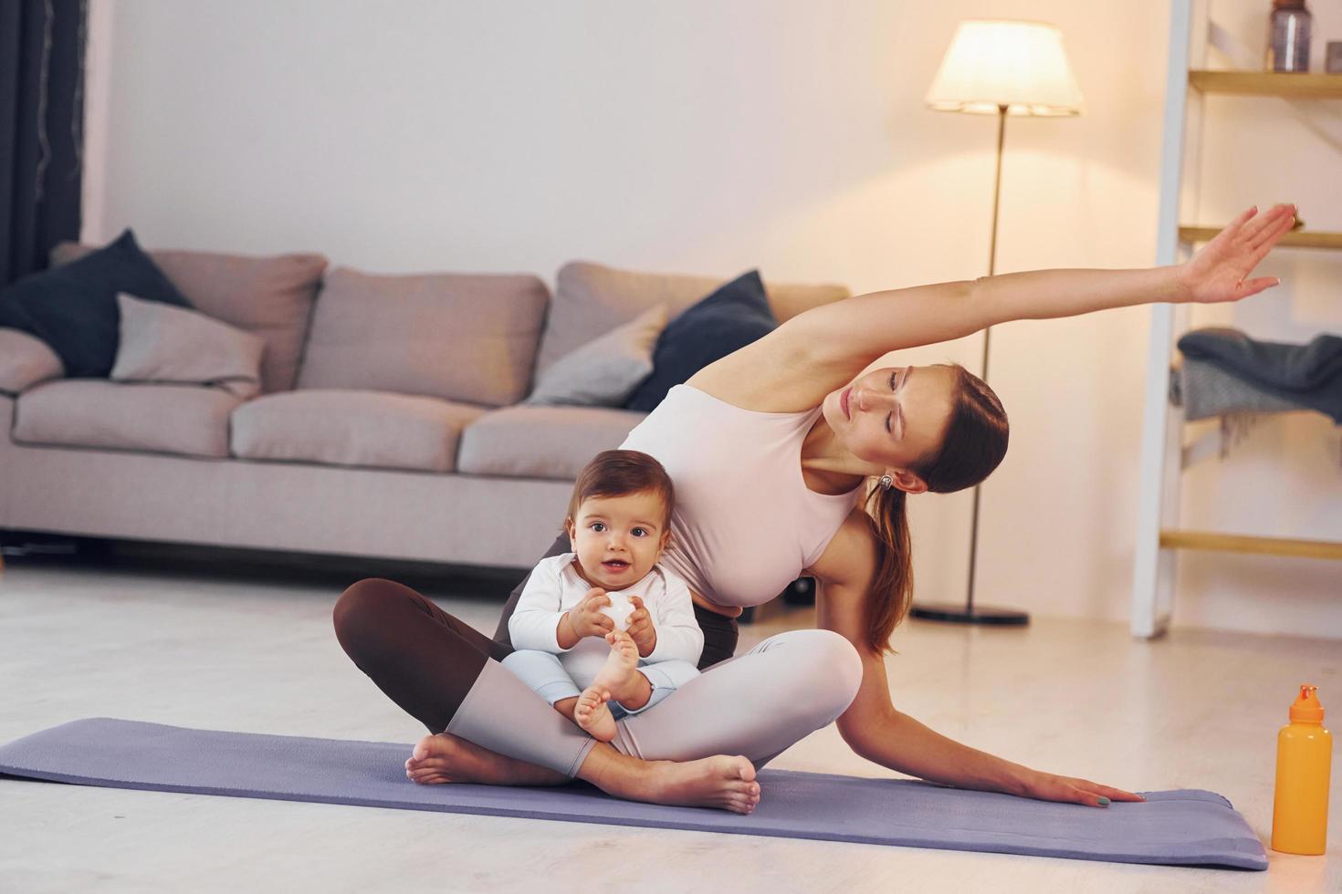 en la estera de yoga. madre con su pequeña hija está en casa juntos foto