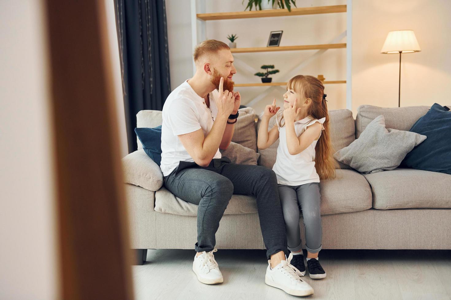 On the sofa. Having fun. Father with his little daughter is at home together photo