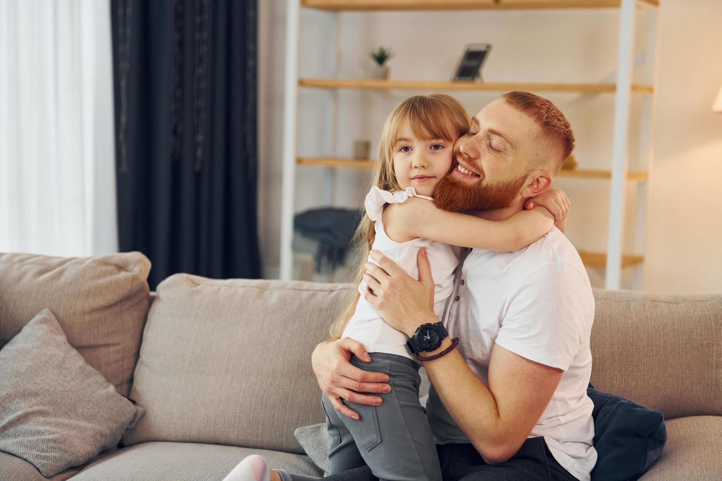 abrazándose unos a otros. padre con su pequeña hija está en casa juntos foto