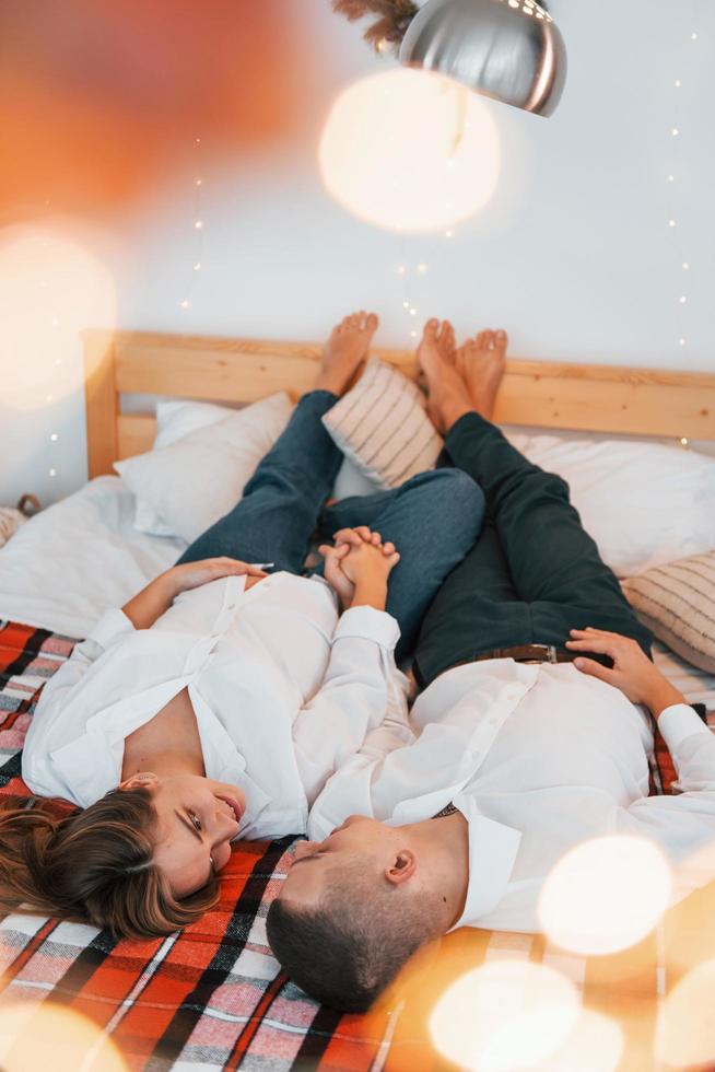 Laying down on the bed. Lovely couple celebrating holidays together indoors photo