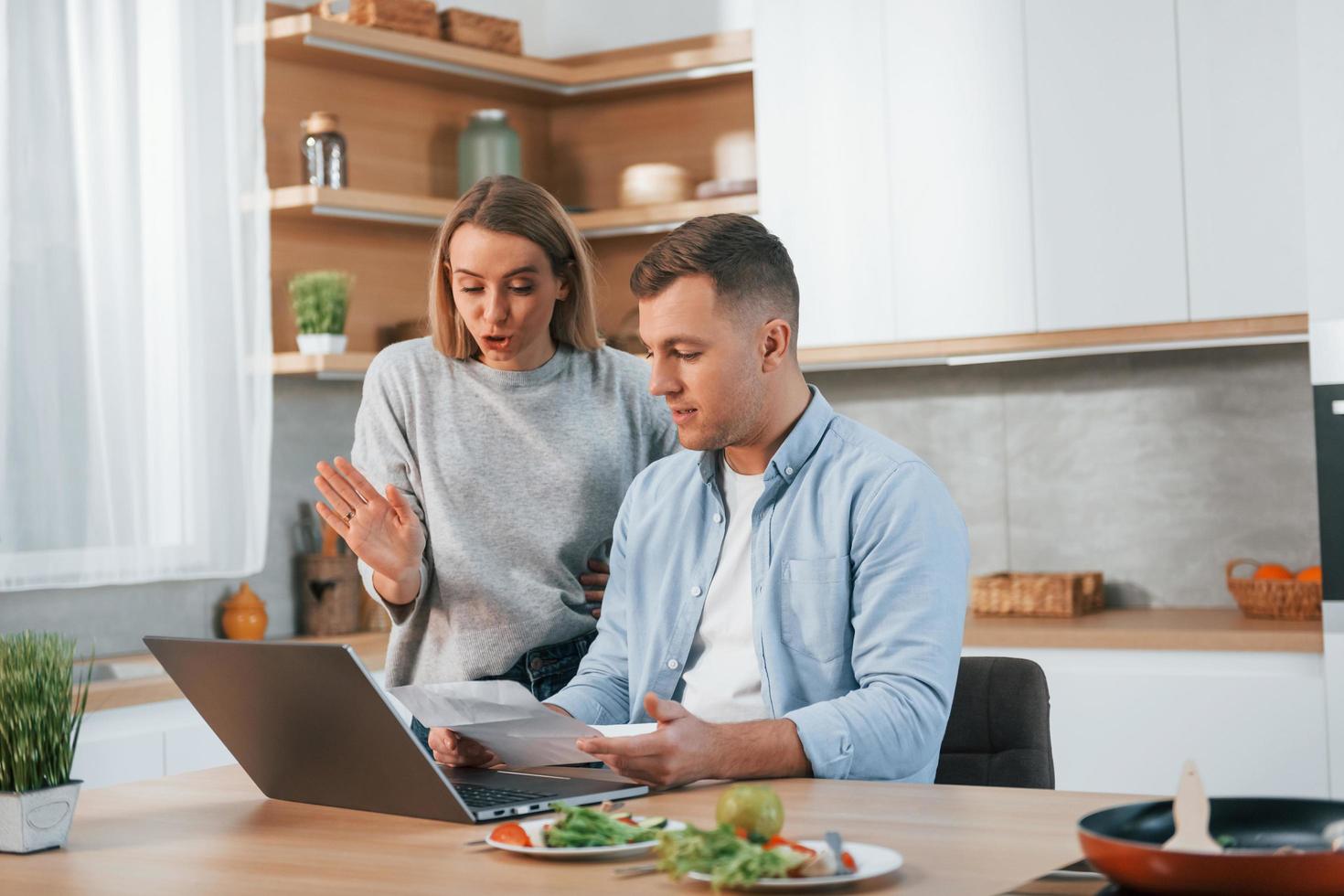 usando Internet. pareja preparando comida en casa en la cocina moderna foto