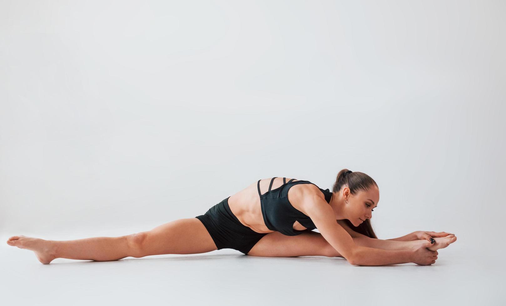 estirando hacia un lado. mujer joven en ropa deportiva haciendo gimnasia en el interior foto