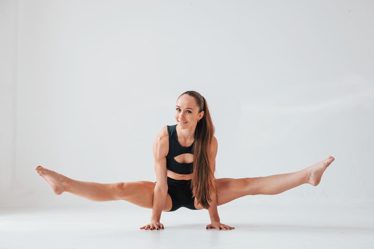 de pie sobre las manos. mujer joven en ropa deportiva haciendo gimnasia en el interior foto