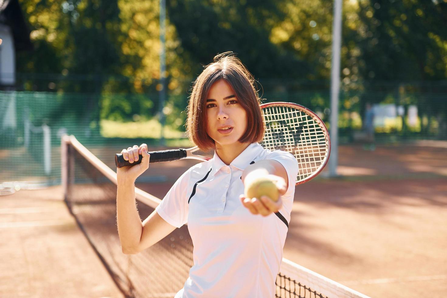 Standing with racket in hand. Female tennis player is on the court at daytime photo