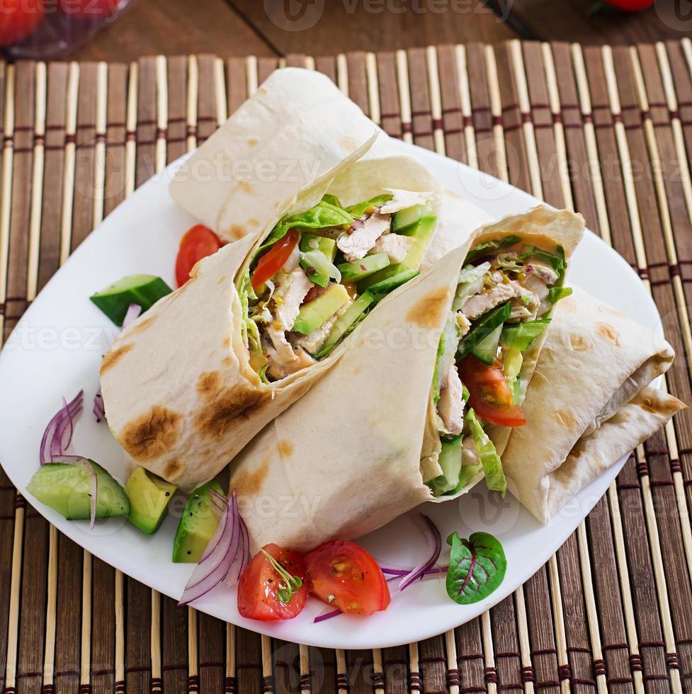 Fresh tortilla wraps with chicken and fresh vegetables on plate photo