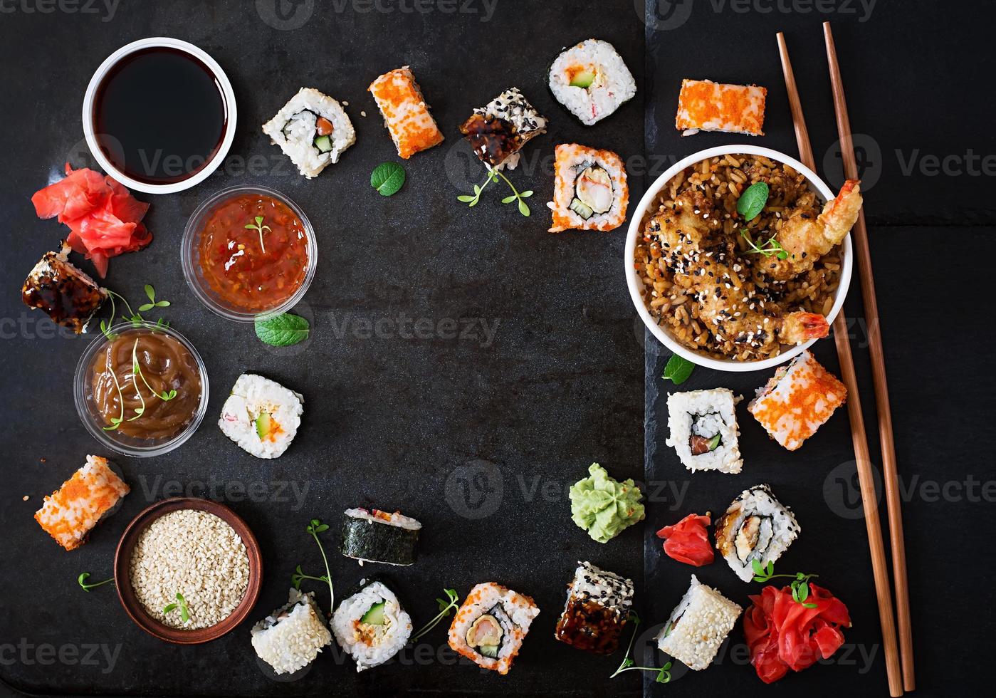 Traditional Japanese food - sushi, rolls, rice with shrimp and sauce on a dark background. Top view photo