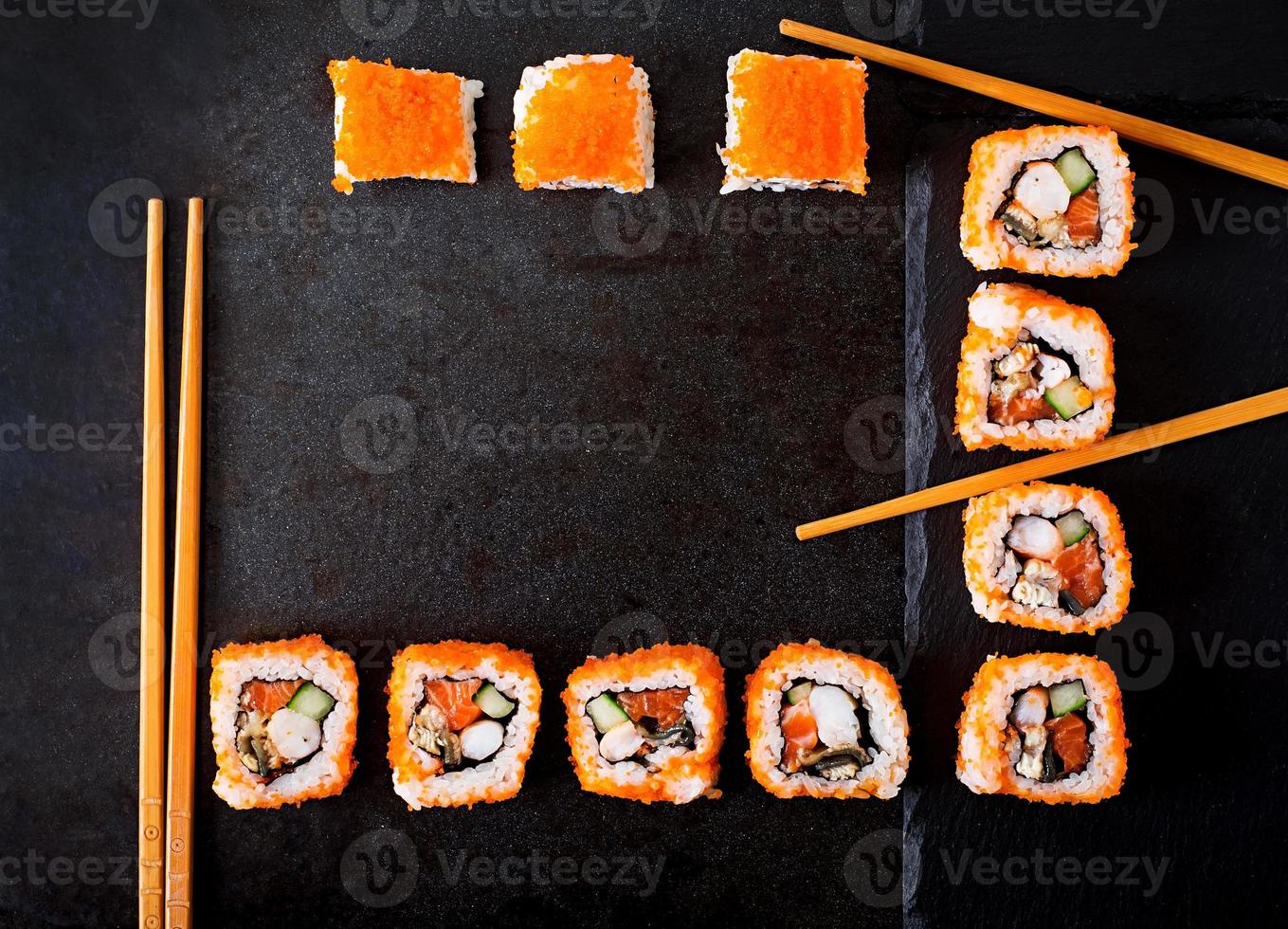comida tradicional japonesa - sushi, rollos y palillos para sushi sobre un fondo oscuro. vista superior foto