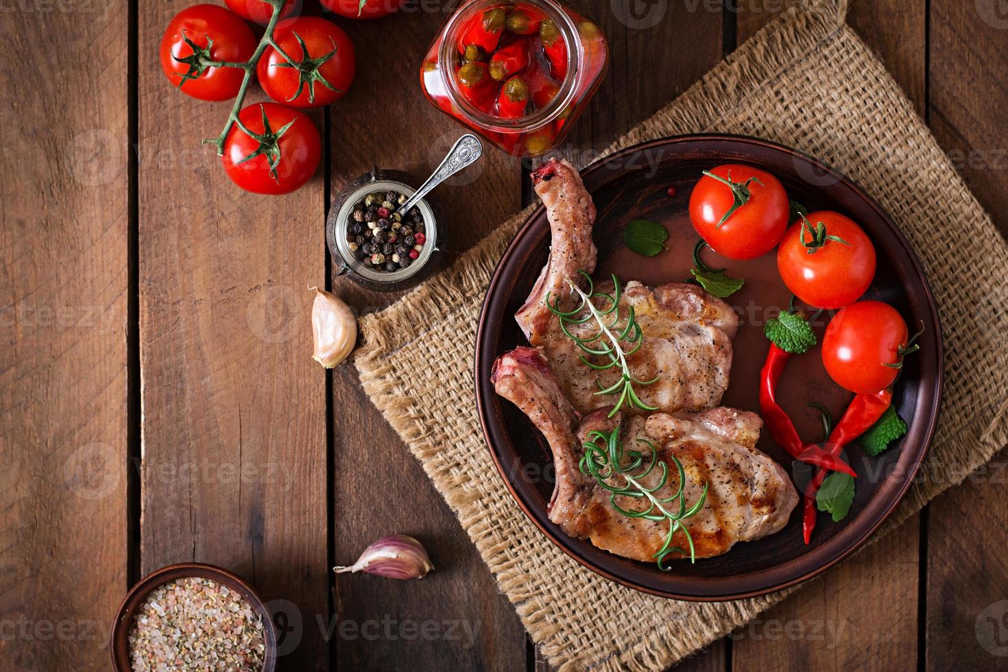 Grilled juicy steak on the bone with vegetables on a wooden background. Top view photo