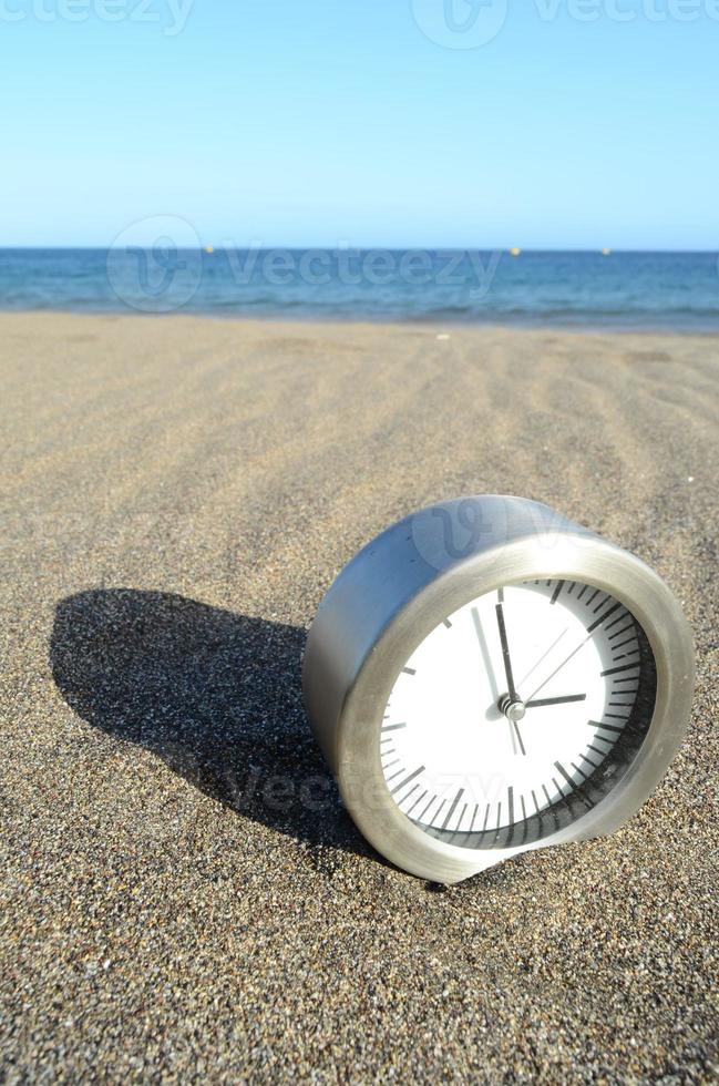 Clock  on the beach sand photo