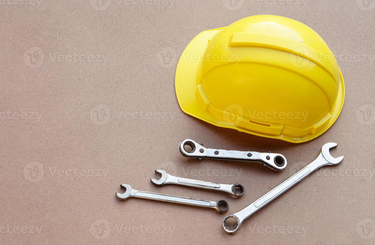 Yellow helmet and wrenches on brown background. Concept, handyman or mechanic tools. Equipment for fixing or repairing, renovation in daily life. photo