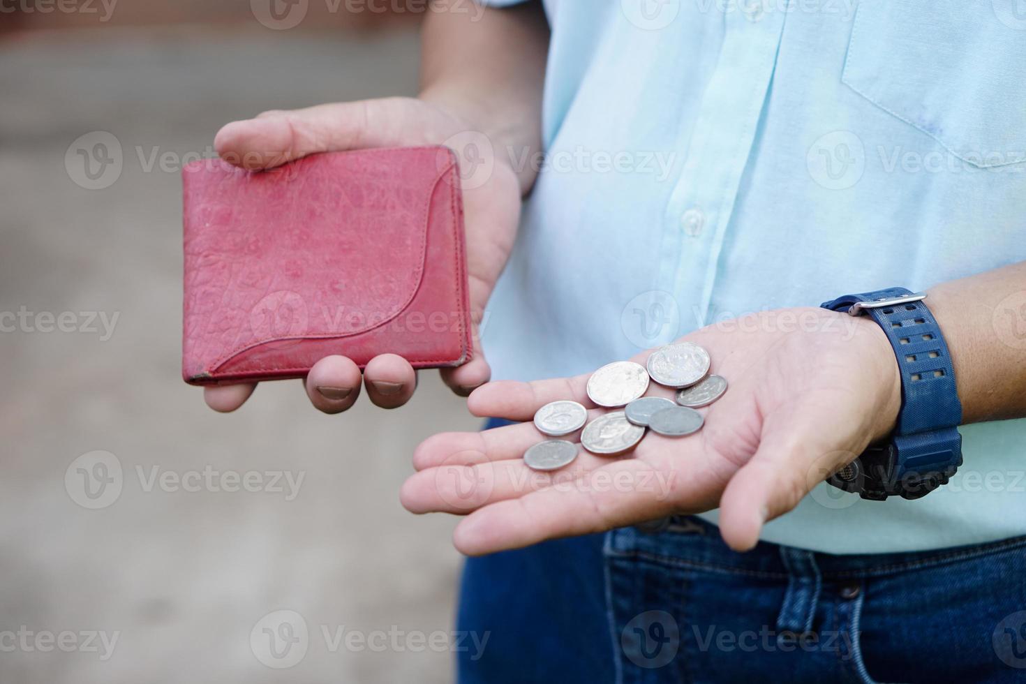 la mano de primer plano sostiene monedas de baht tailandés y billetera vacía. concepto, sin dinero, crisis económica. problemas financieros. rompió o menos dinero al final del mes. foto