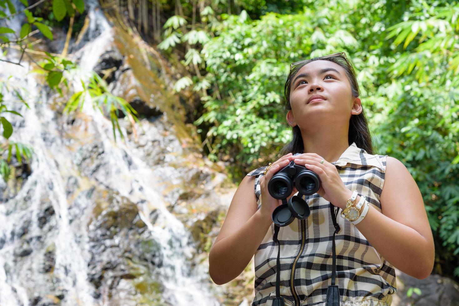 Girl using binoculars in forest photo