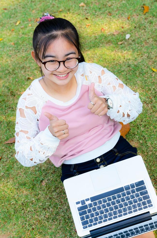 Cute girl is happy with notebook on grass photo