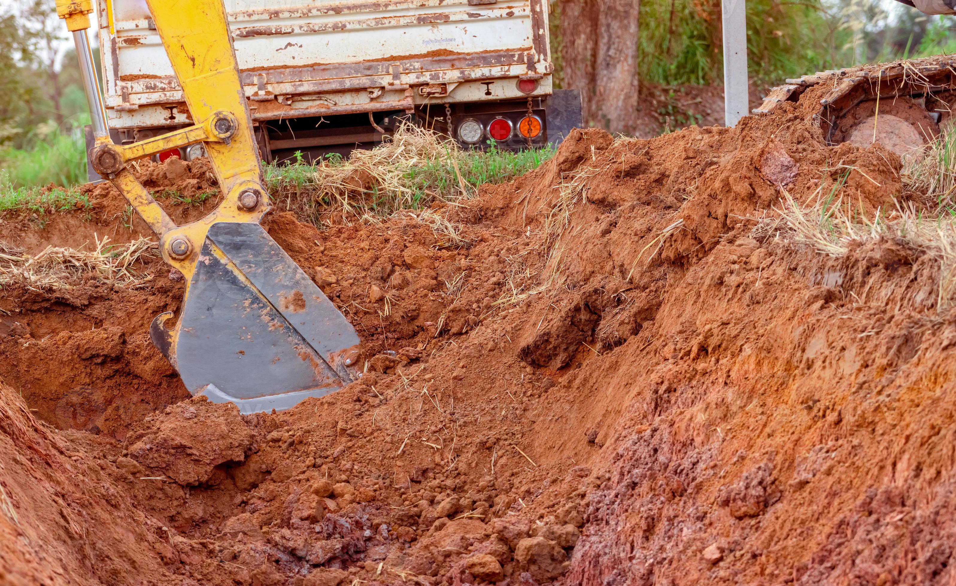 Excavator bucket digging soil for loading to truck. Earthwork. Dirt