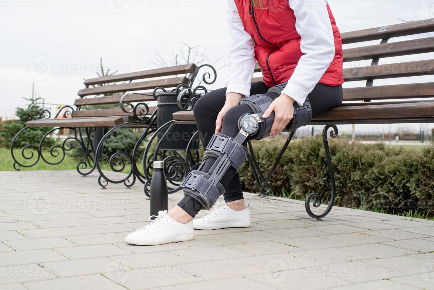 Woman wearing knee brace or orthosis after leg surgery, walking in the park photo