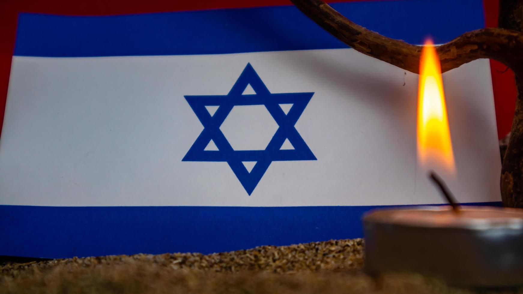 Israeli flag and candles burning in front of it, Holocaust memory day photo