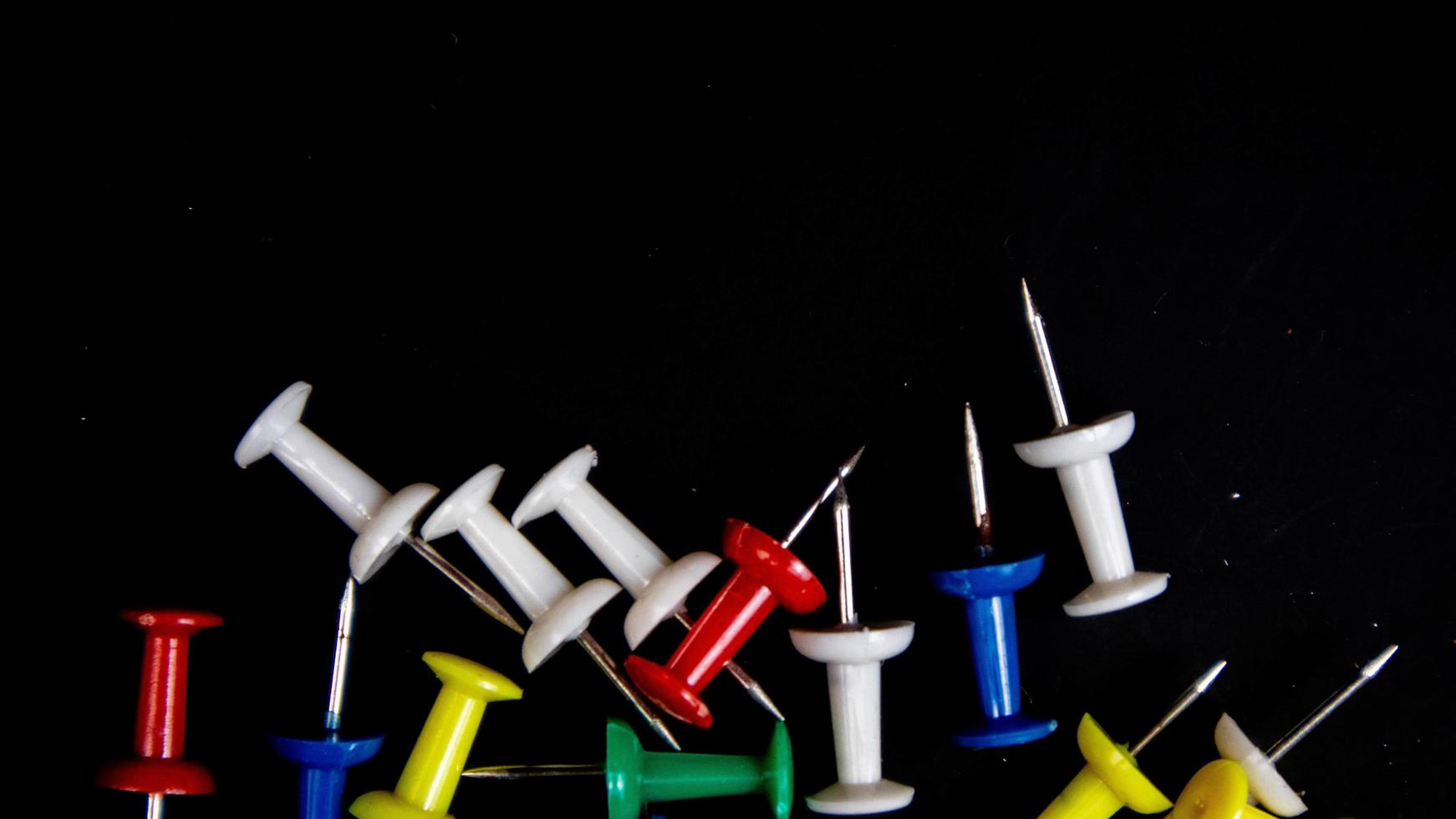 multicolored thumbtacks on a black background photo