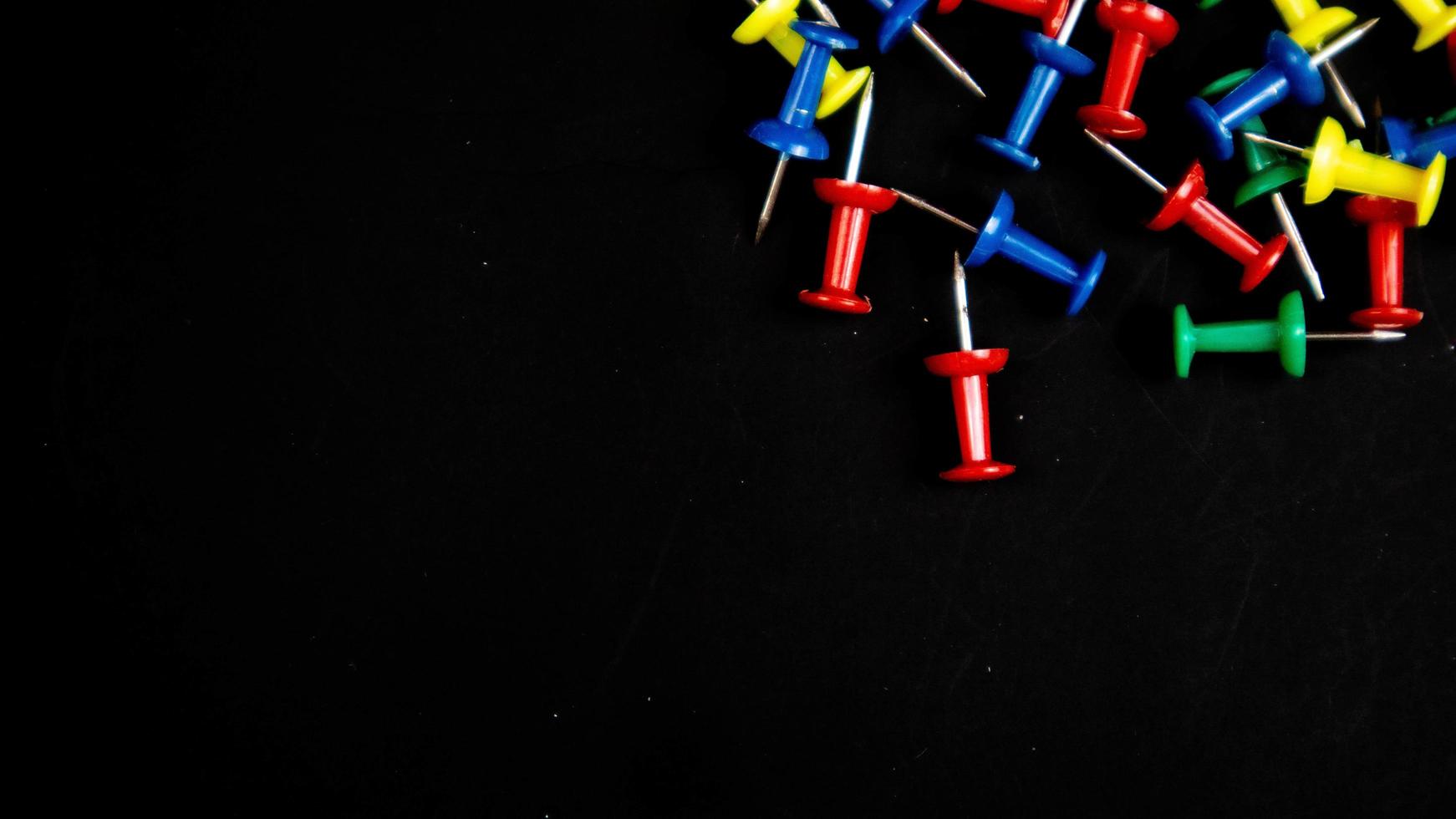 multicolored thumbtacks on a black background photo