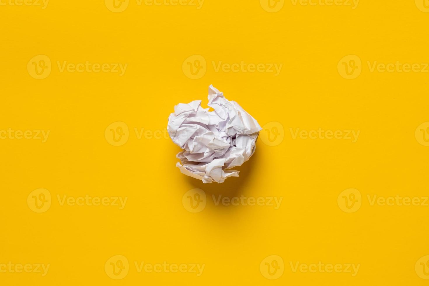 Crumpled sheet of white paper on a yellow background. Copy space. Top view. photo