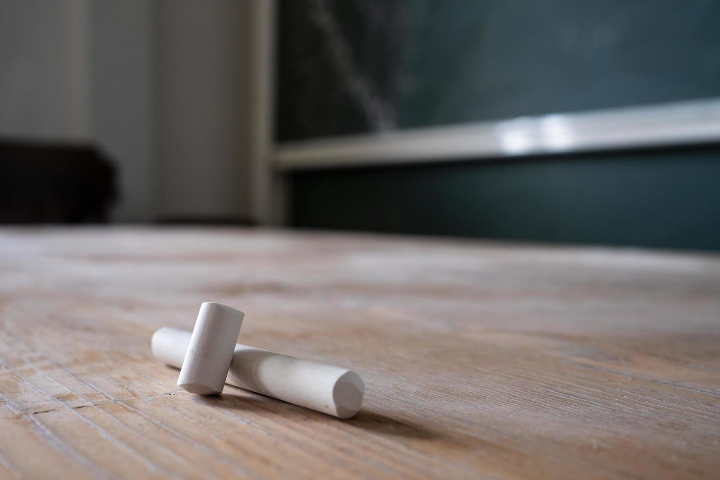 Pieces of white chalk lie on the table, against the background of the blackboard in the classroom. Education concept. photo