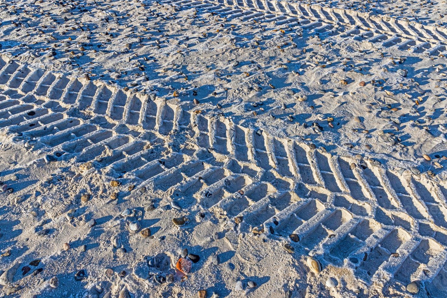 Image of tire tracks in the sand of a beach during the day photo