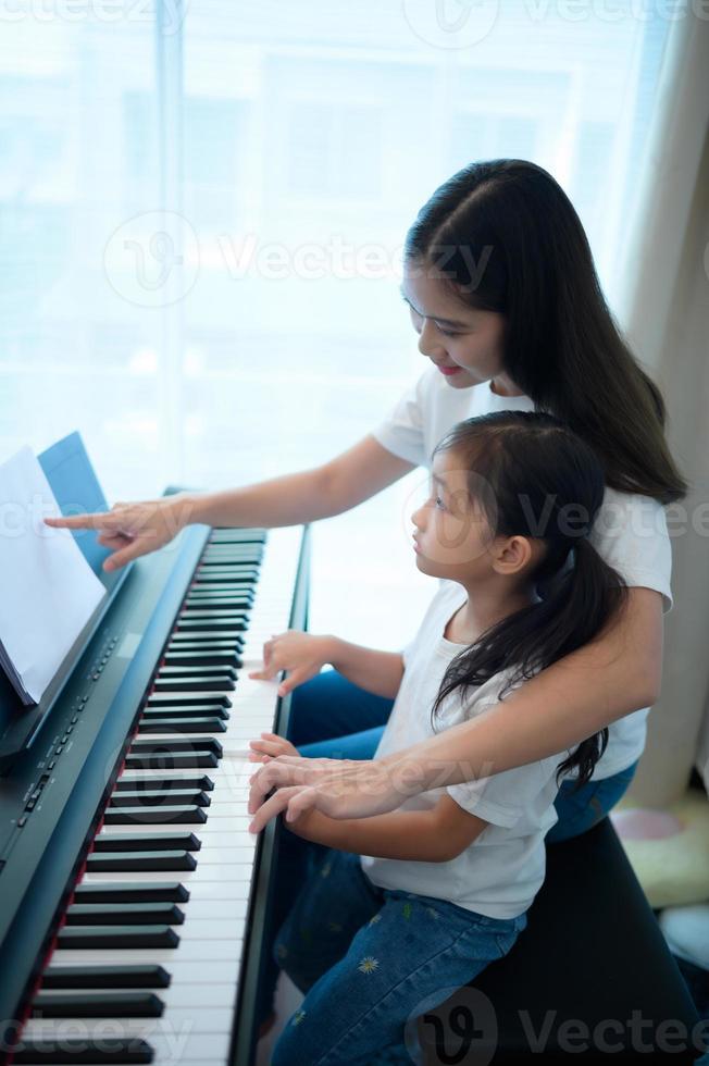 Family vacation, other helping daughter practice in her piano lessons photo