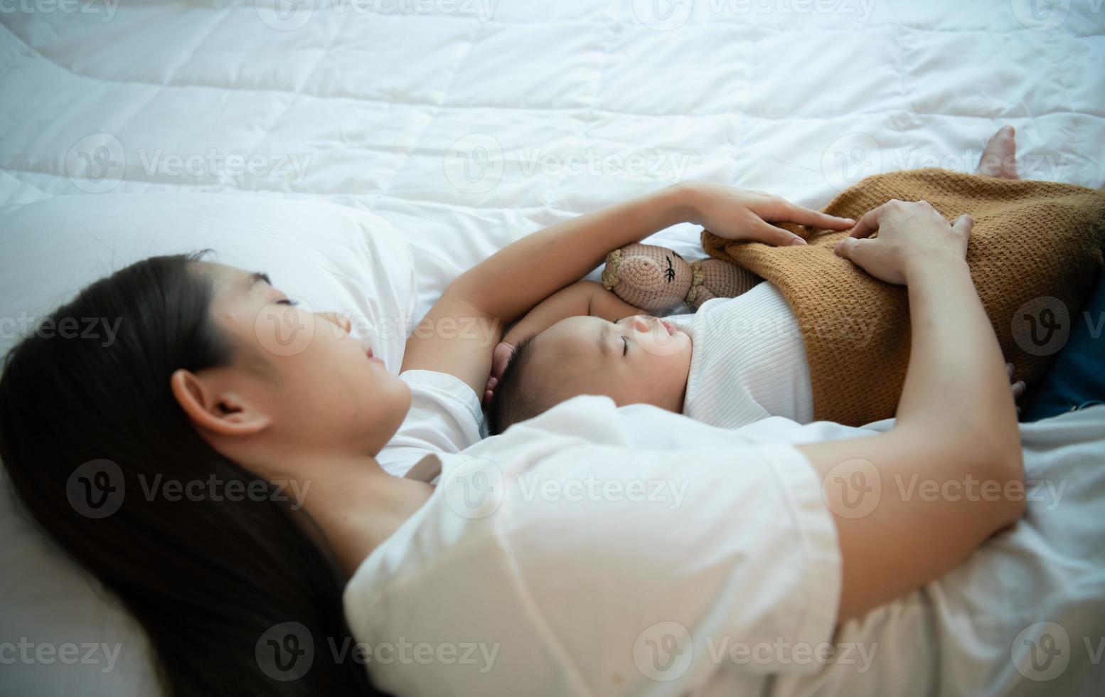 A mother must sleep and rest with her newborn baby. In the white bedroom, warm sunlight in the evening of the day. photo