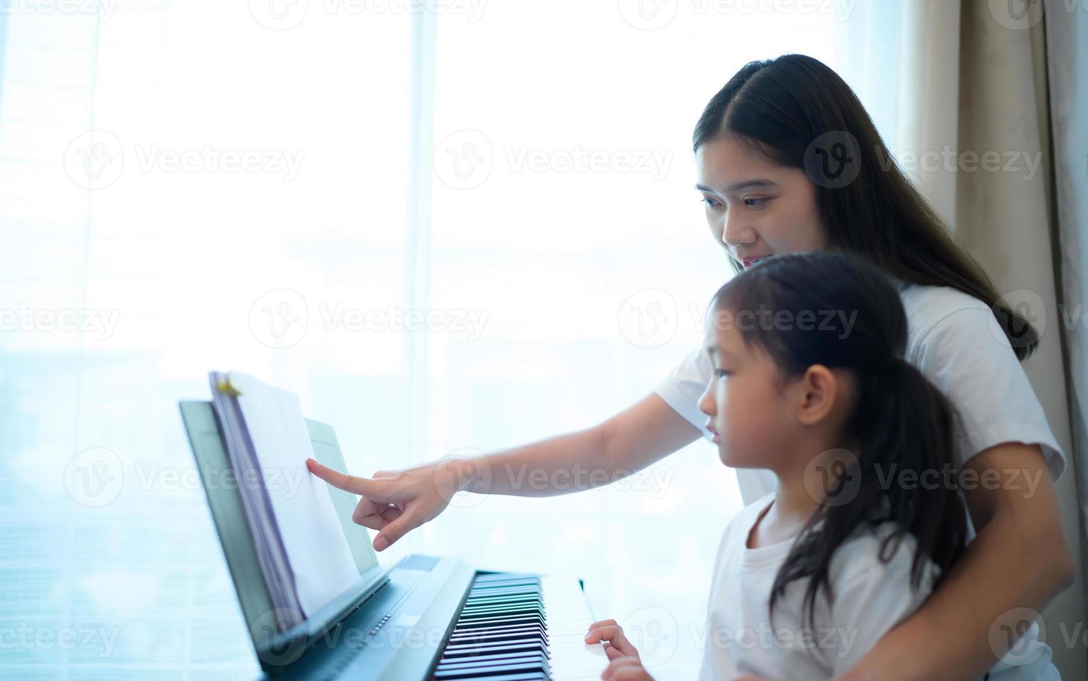 Family vacation, other helping daughter practice in her piano lessons photo