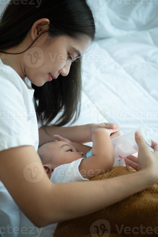 madre joven abrazando a su hijo recién nacido para adormecer al bebé mientras bebe leche foto