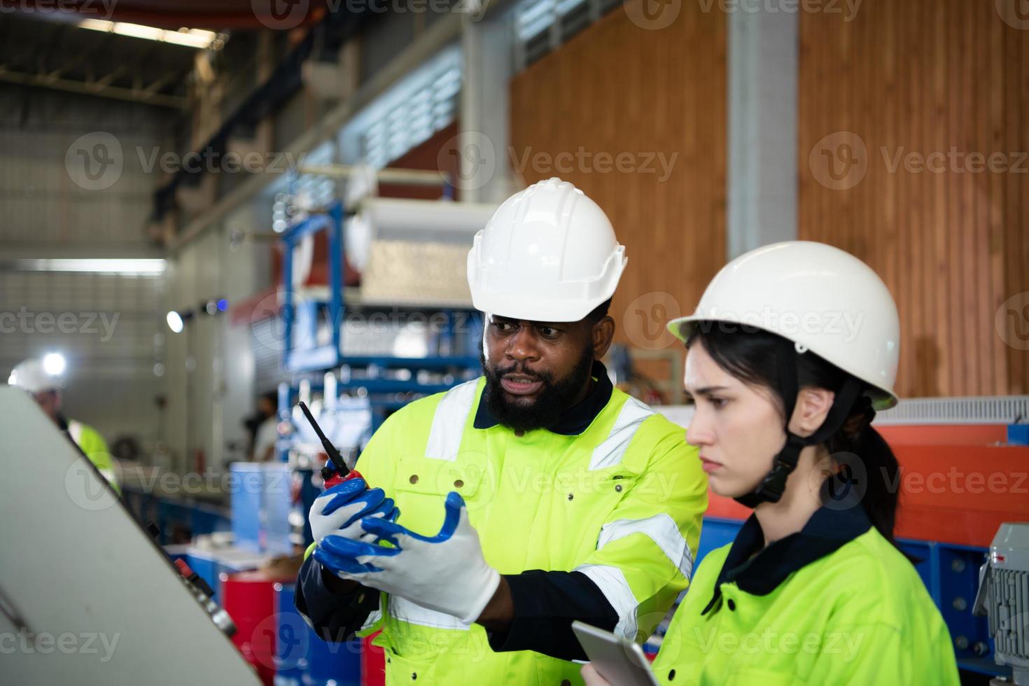 Young female engineer learning to run machinery at a factory with veteran engineers photo