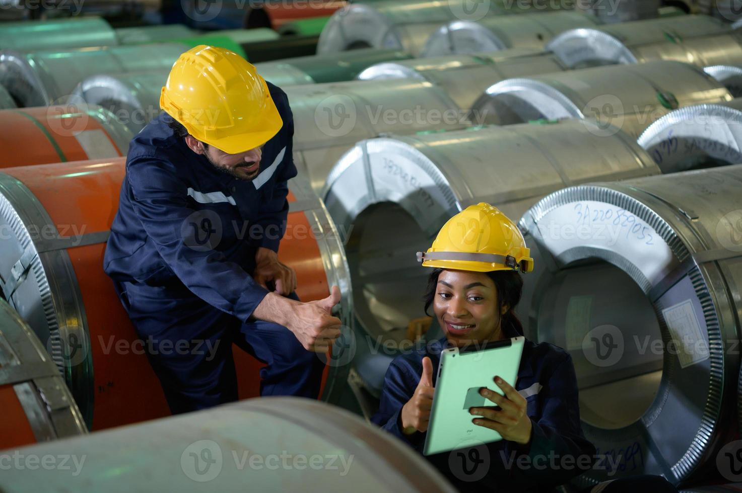 joven ingeniera aprendiendo a operar maquinaria en una fábrica con ingenieros veteranos foto