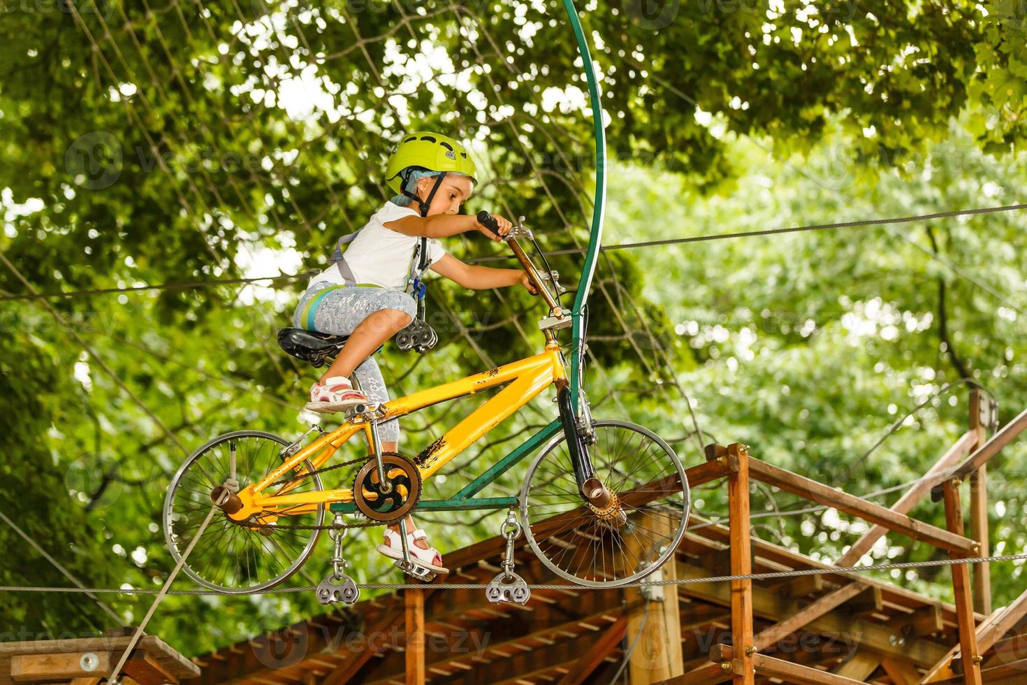 Adorable little girl enjoying her time in climbing adventure park on warm and sunny summer day photo