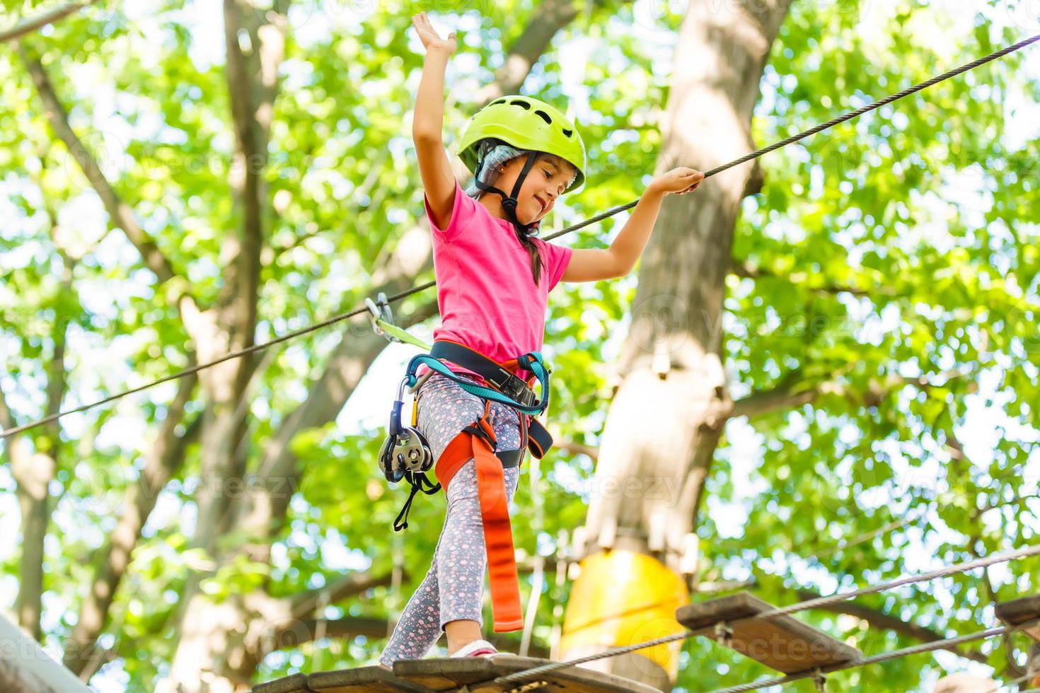 parque de cuerdas de escalada de aventura - niños en el parque de cuerdas del curso en casco de montaña y equipo de seguridad foto