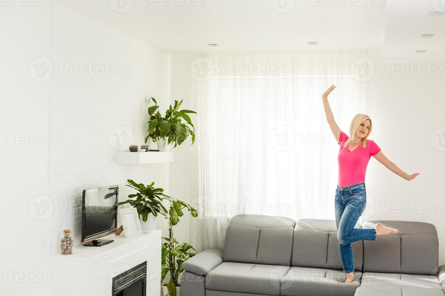 Happy mommy jumping on sofa together, baby sitter or mother playing having fun at home, young mum spending time photo