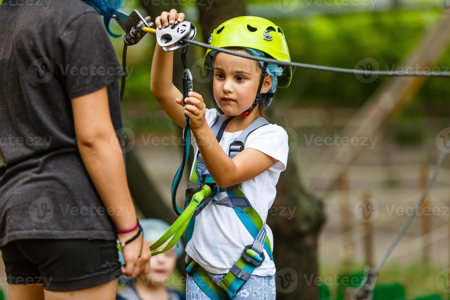 Happy school girl enjoying activity in a climbing adventure park on a summer day photo