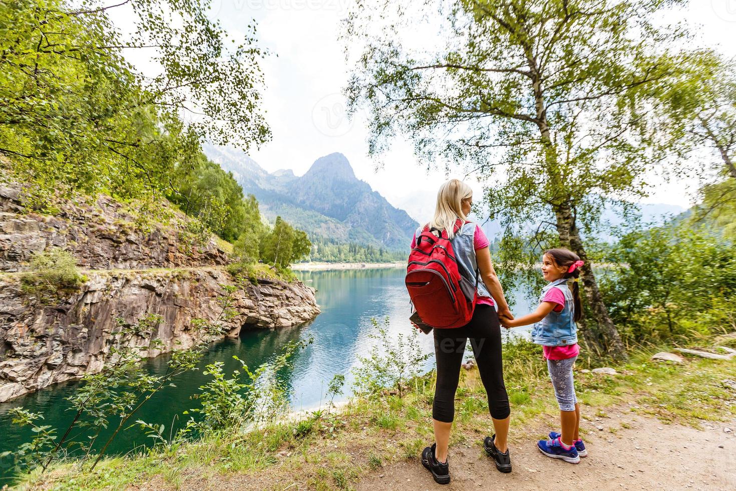 Hikers with backpack looking at mountains, alpine view, mother with child photo