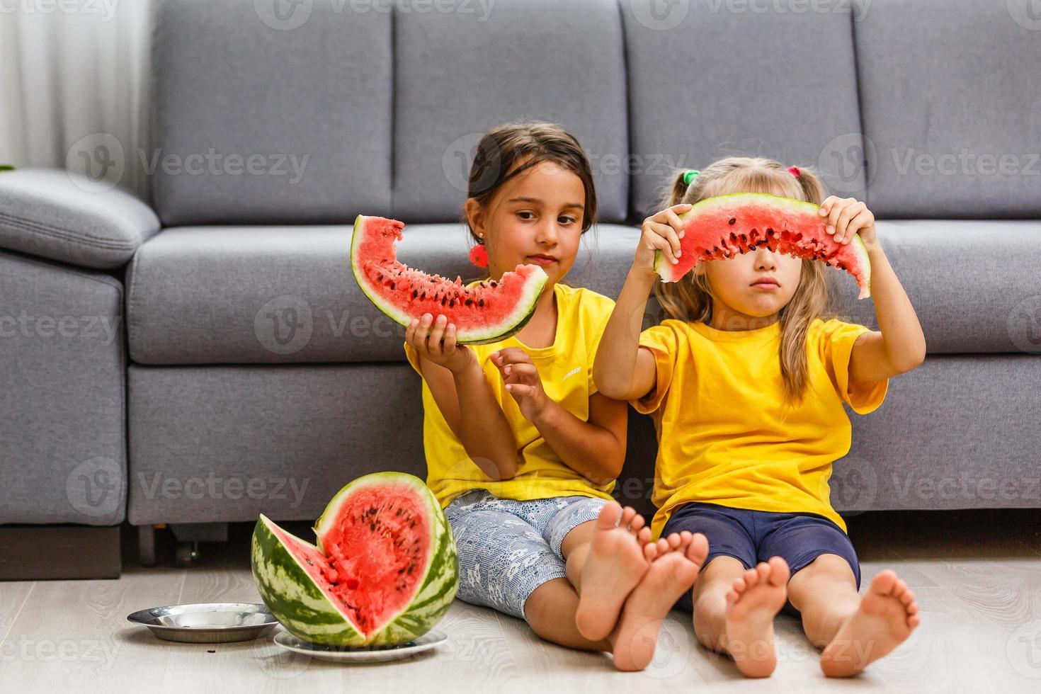 Child eating watermelon, two little girls eat watermelon at home photo