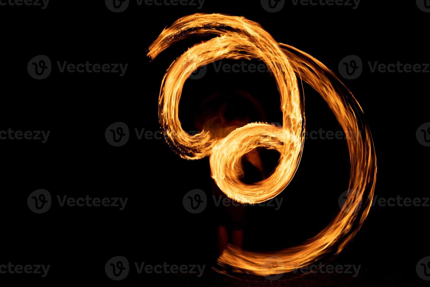 A beautiful shot of a person doing a fire Poi show in the dark photo
