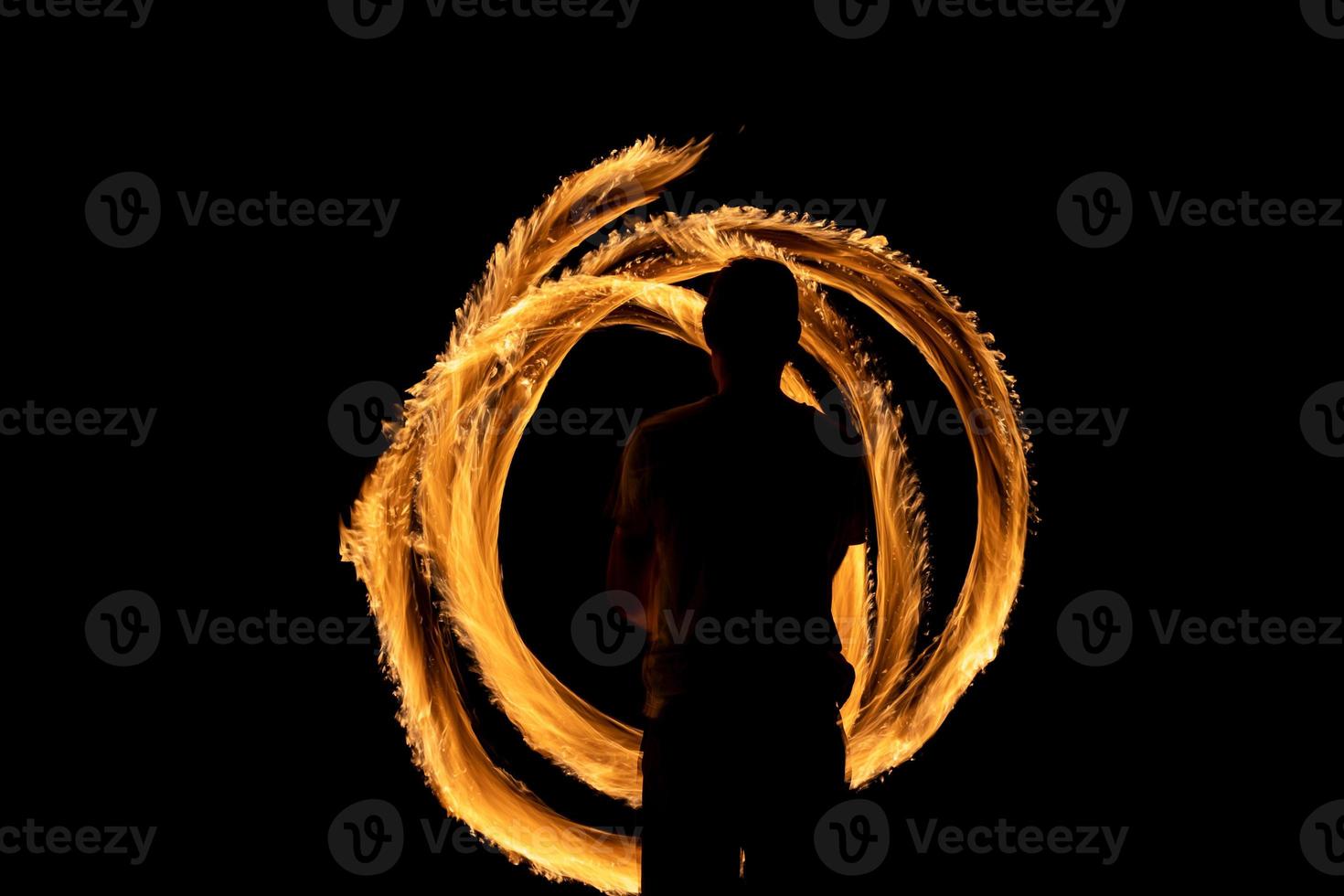 A beautiful shot of a person doing a fire Poi show in the dark photo