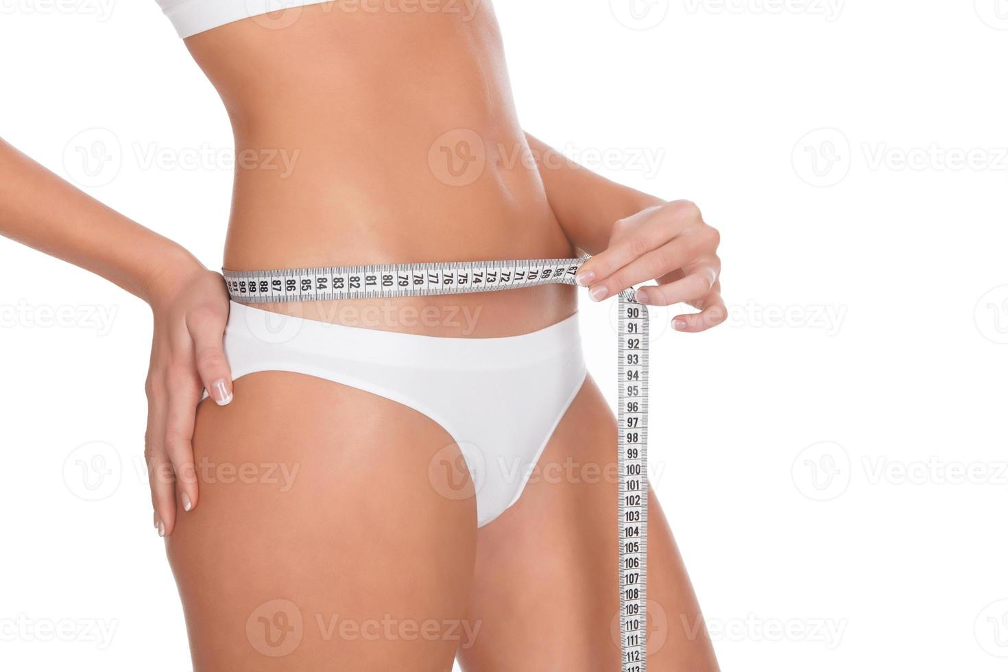 fit young woman measuring her waistline, white background photo