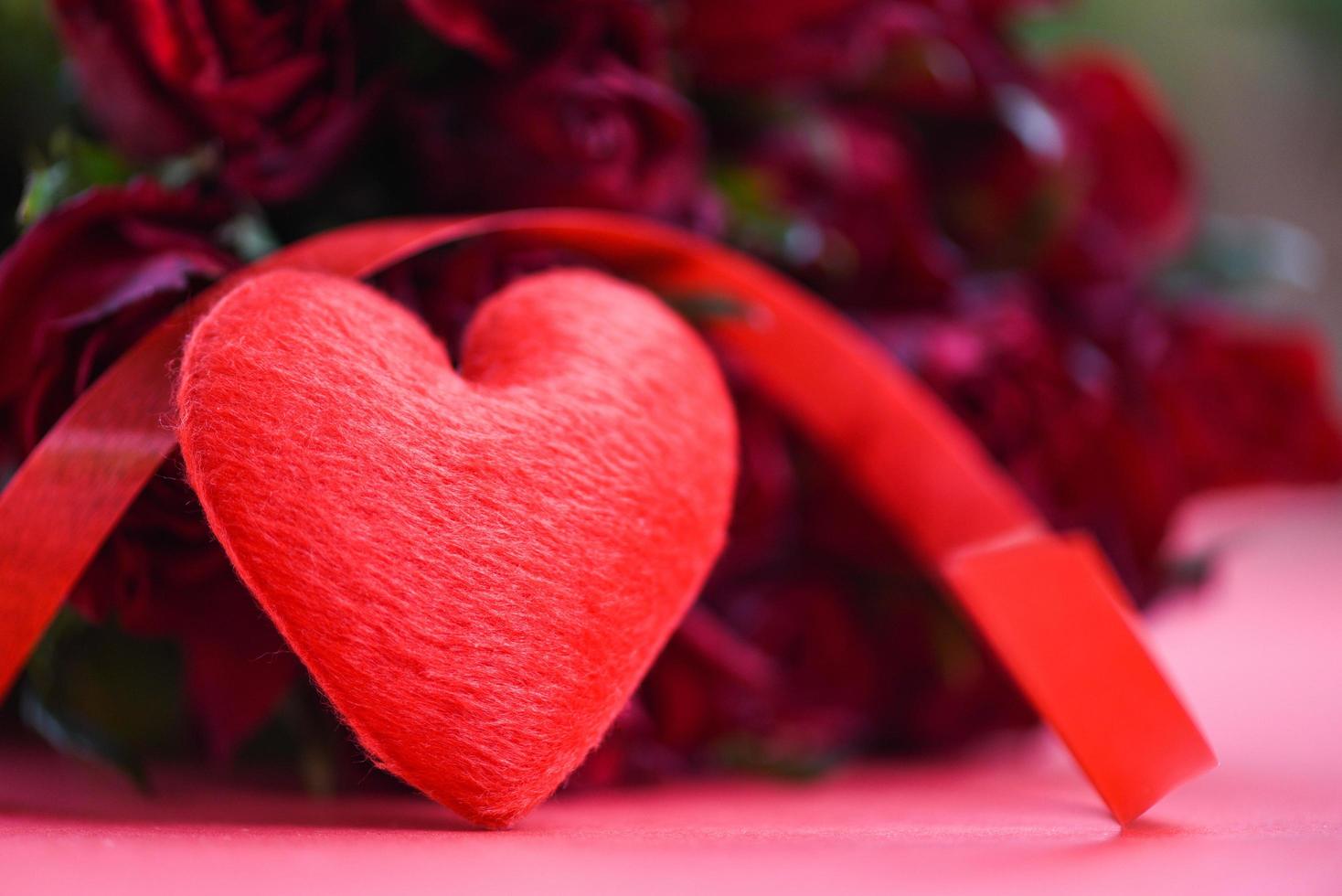 ramo de rosas de flores sobre fondo rojo corazón rojo con cinta y rosa amor romántico concepto de día de san valentín foto