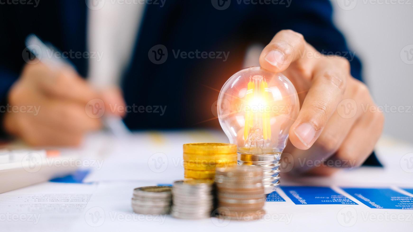 Businessman using a pen from financial statistics, holding a light bulb, with ideas, with innovation and creativity. photo