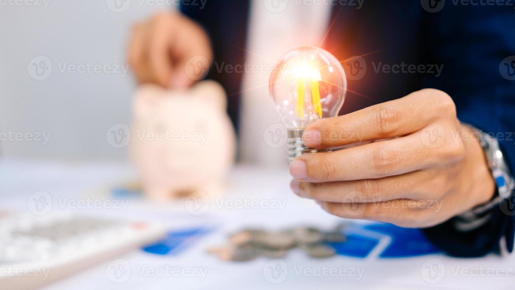 Businessman using a pen from financial statistics, holding a light bulb, with ideas, with innovation and creativity. photo