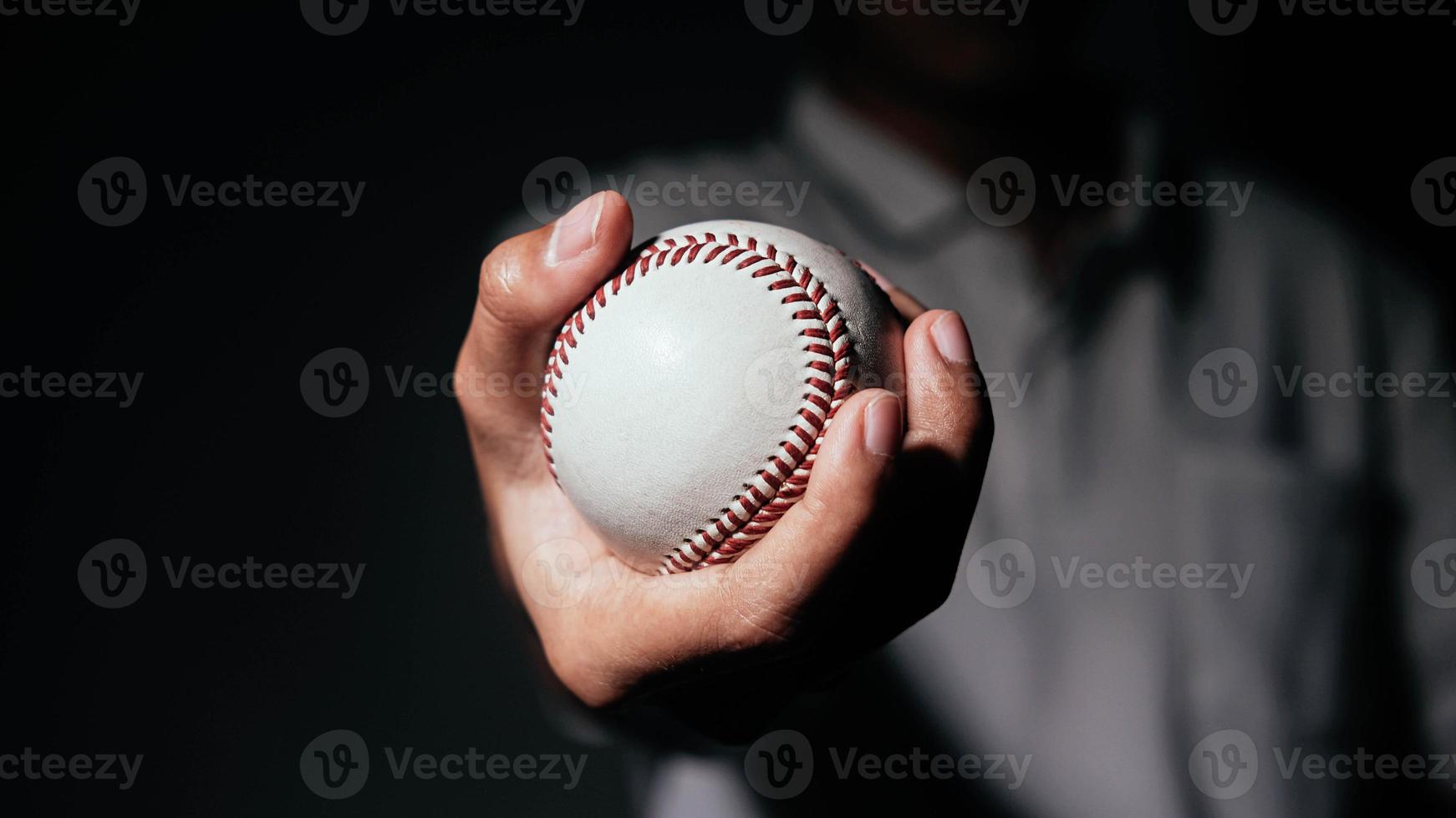 Selective focus of man holding baseball ball isolated on black background. photo