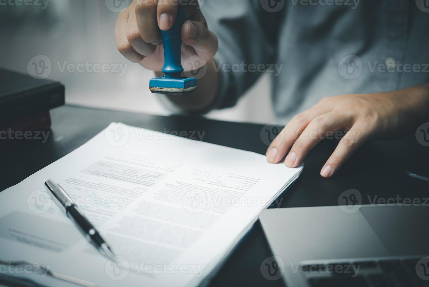 Man stamping approval of work finance banking or investment marketing documents on desk. photo