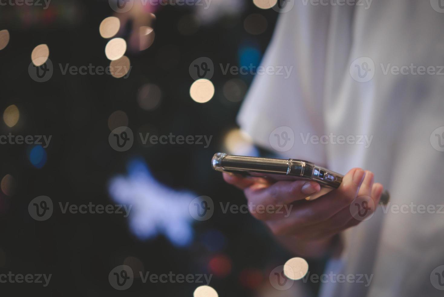 manos masculinas usando smartphone por la noche en la ciudad con bokeh de fondo. foto