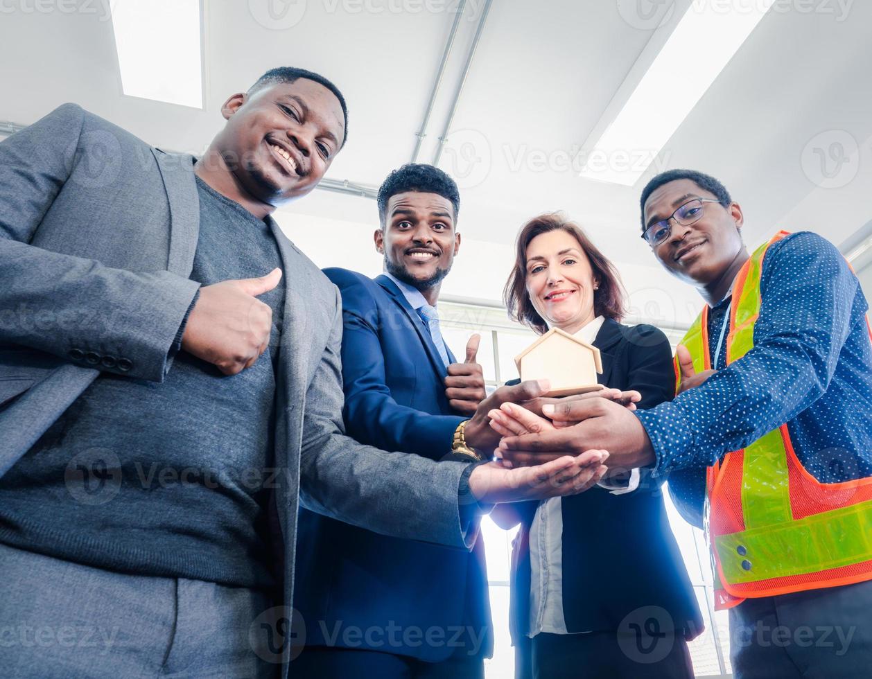 Businesspeople's multiracial colleagues brainstorm with house models and blueprints at the office. Professional construction team discussing the arrangement of service lines at the new building. photo