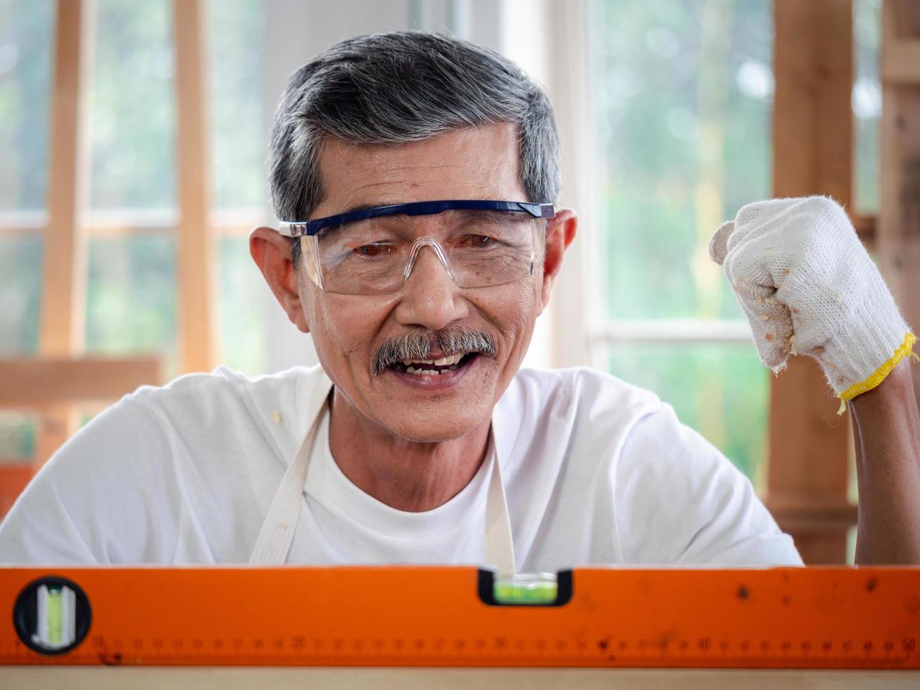 precisión y calidad. carpintero senior feliz comprobando el nivel de un tablón de madera. concepto de medición foto