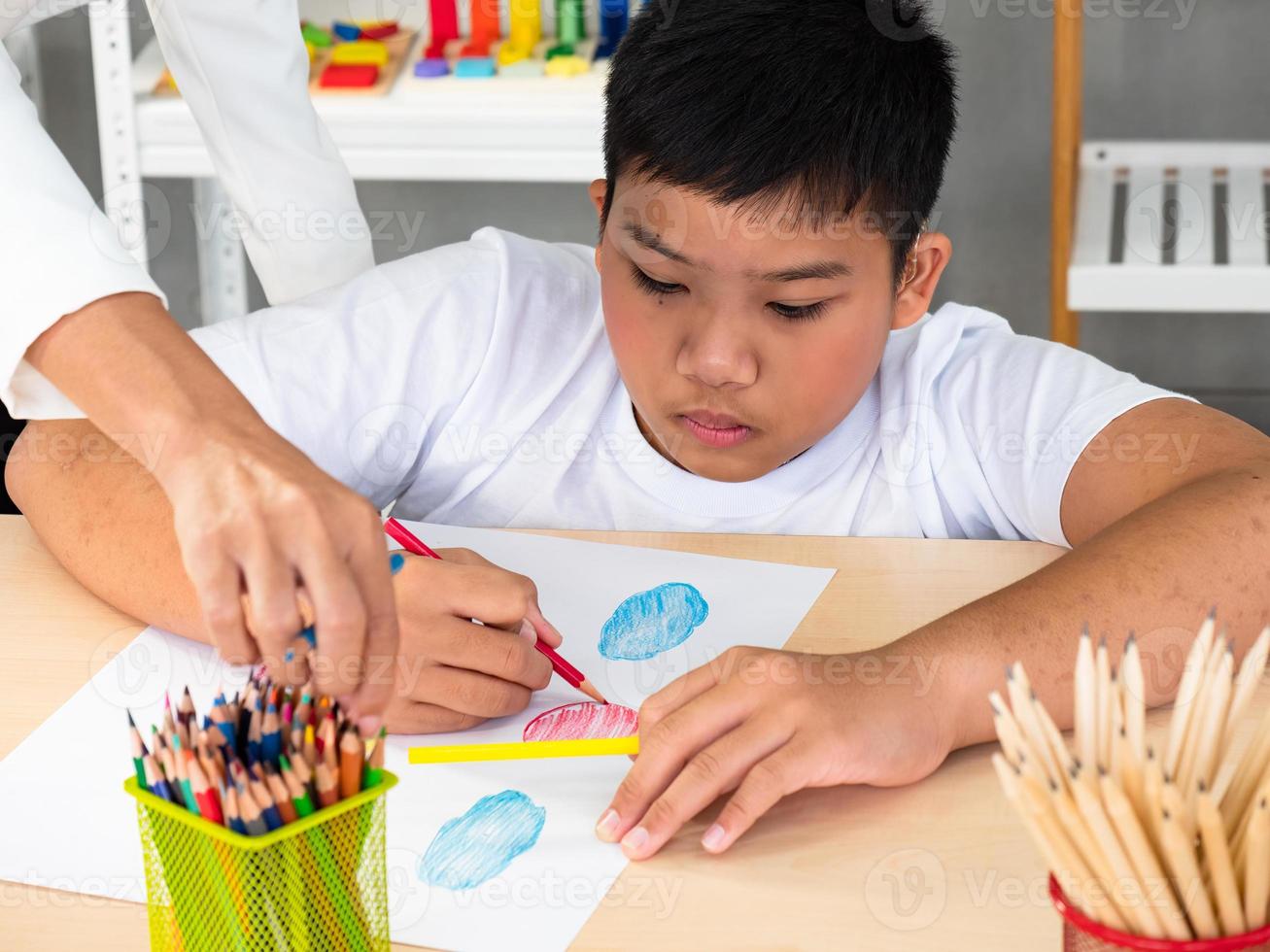 A cheerful group creative arts class for kids and their teacher in the school classroom, happy schoolkids playing an interesting board game during a lesson in the classroom photo